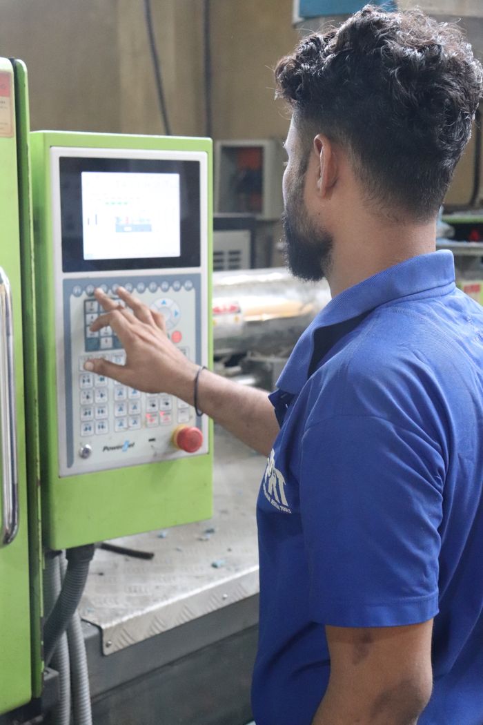 A factory worker in Karachi uses a control panel of an industrial machine.
